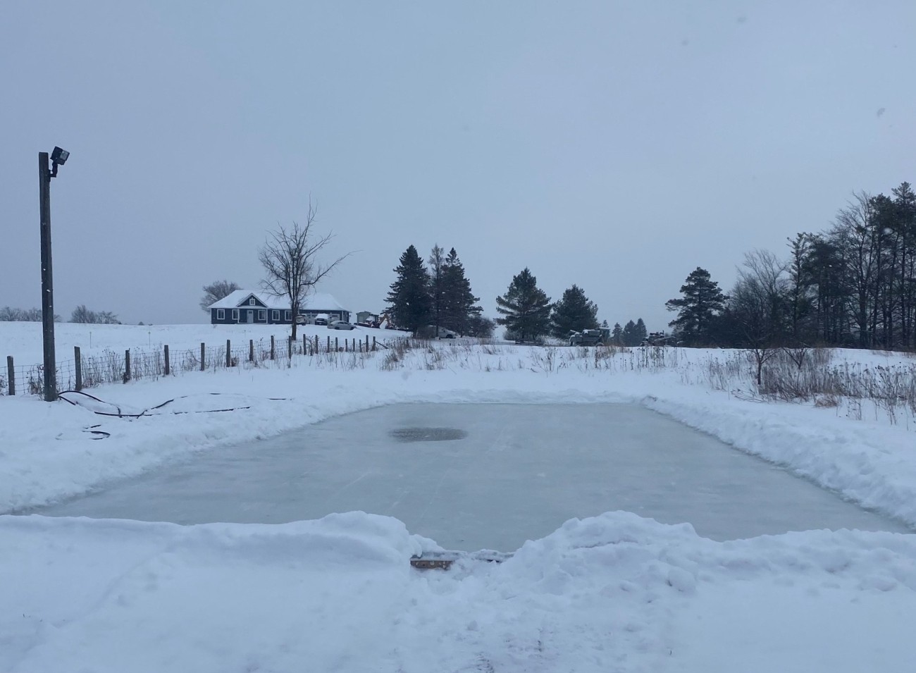 Outdoor ice rink in rural setting on an overcast day.