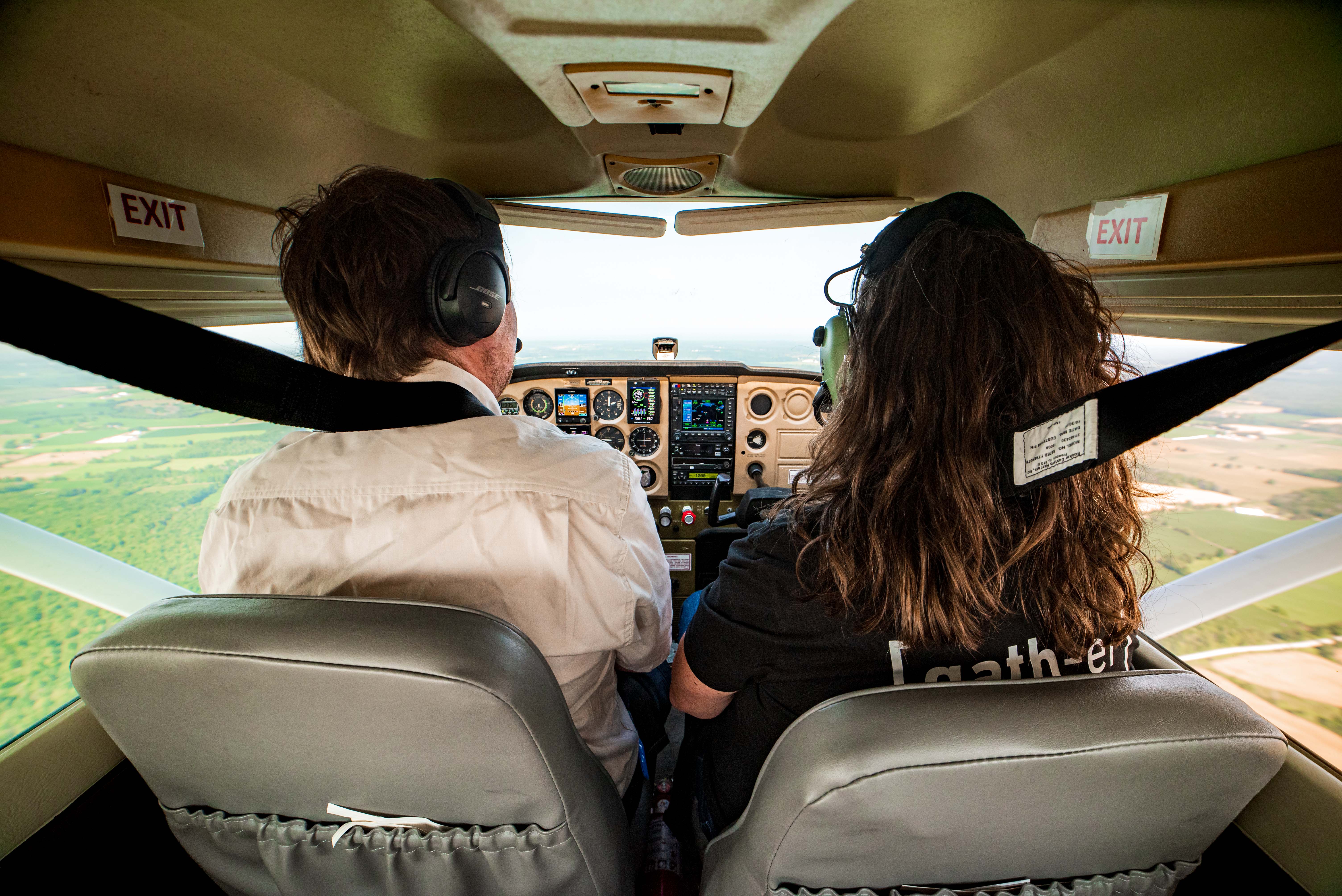 A pilot and passenger inside the cockpit of a small aircraft.