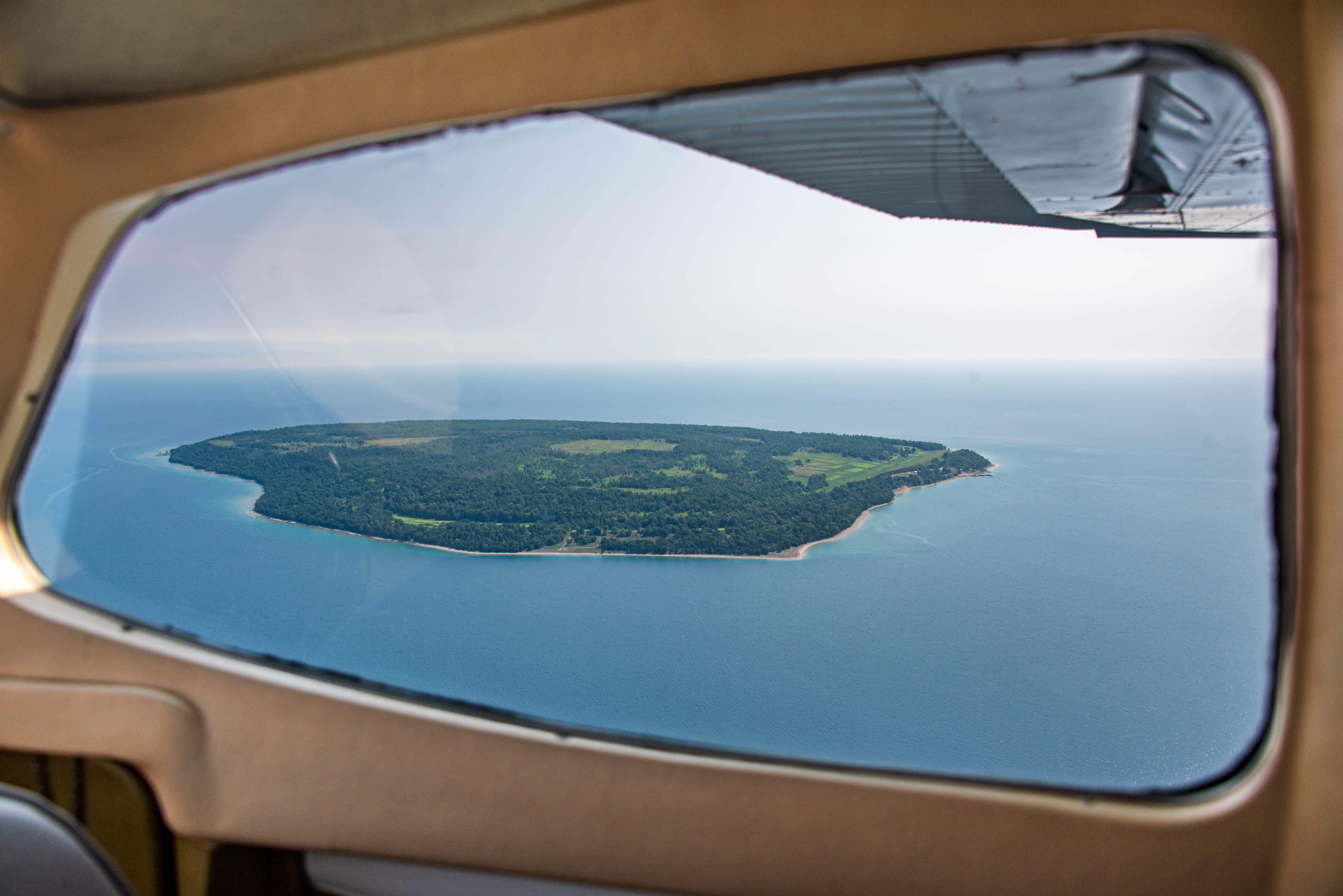 An island seen through the window of a small aircraft.