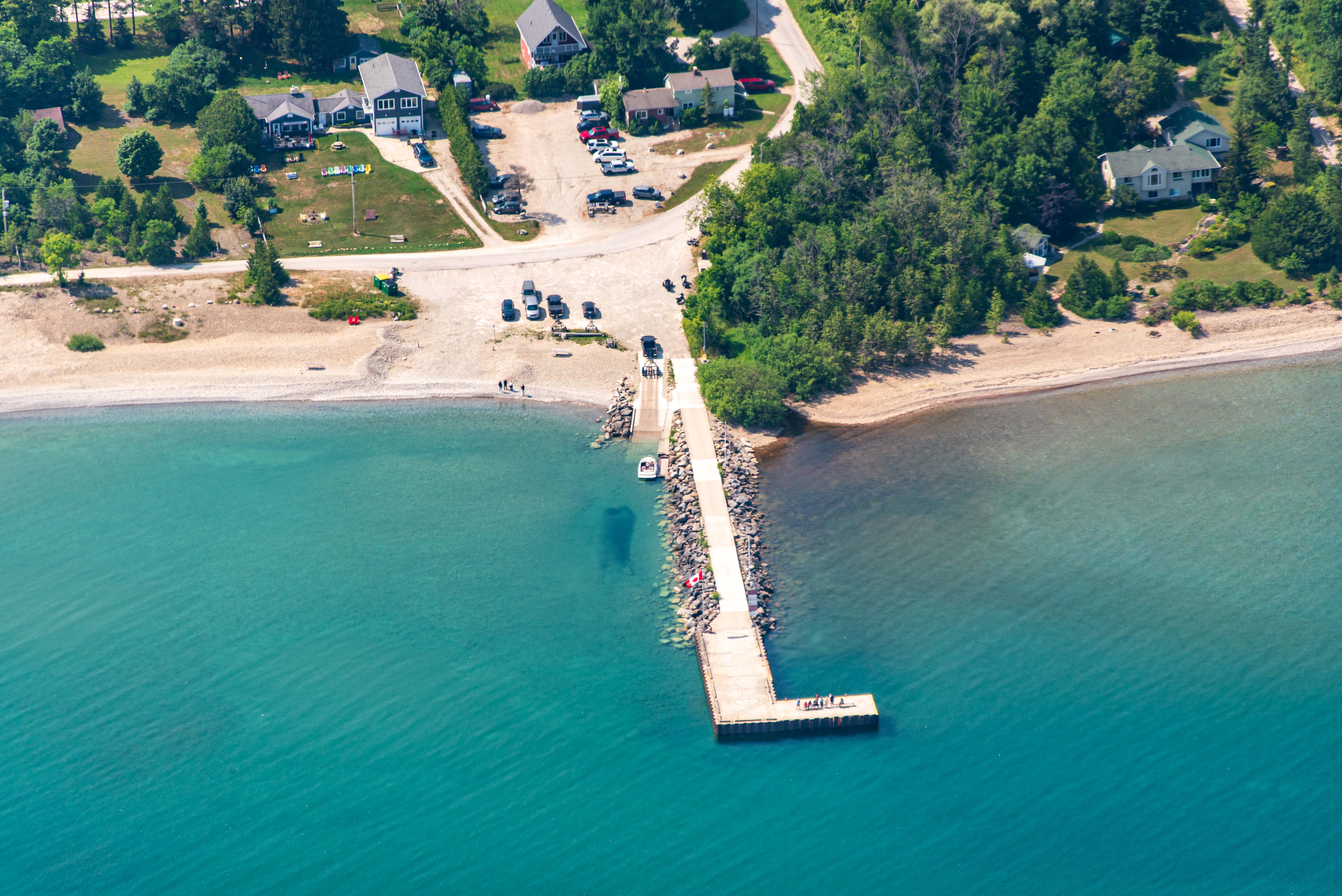 Aerial view of a dock and vibrant blue water. People are visible on the dock.
