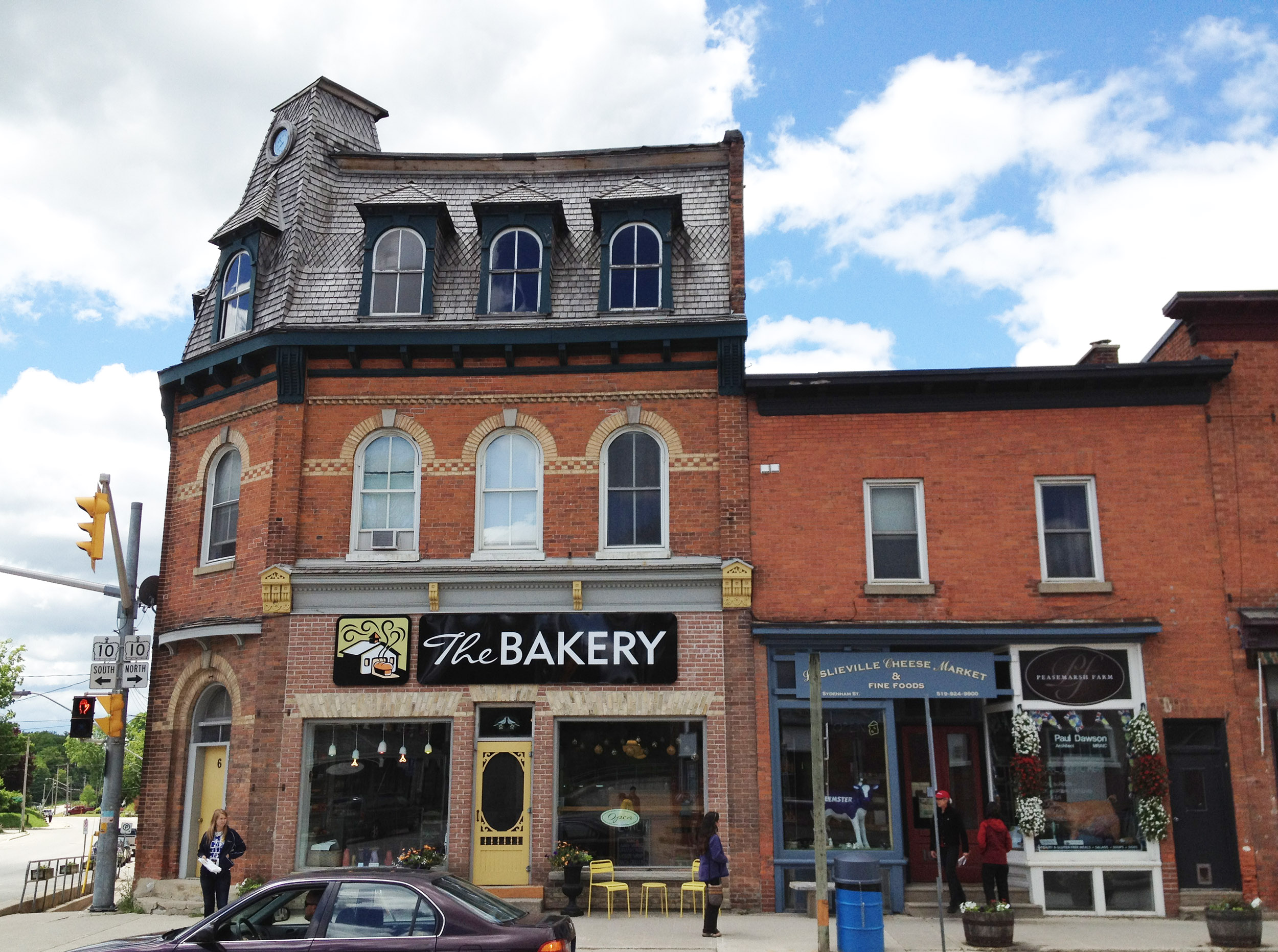 Brick downtown storefronts, including a bakery, on a sunny day.