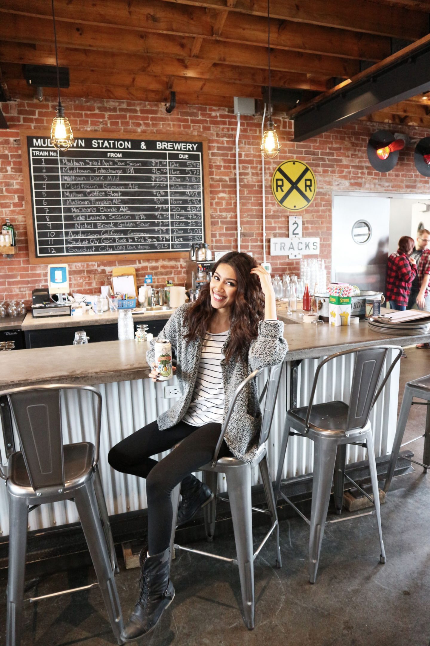 Seated at a bar, a woman smiles at the camera.