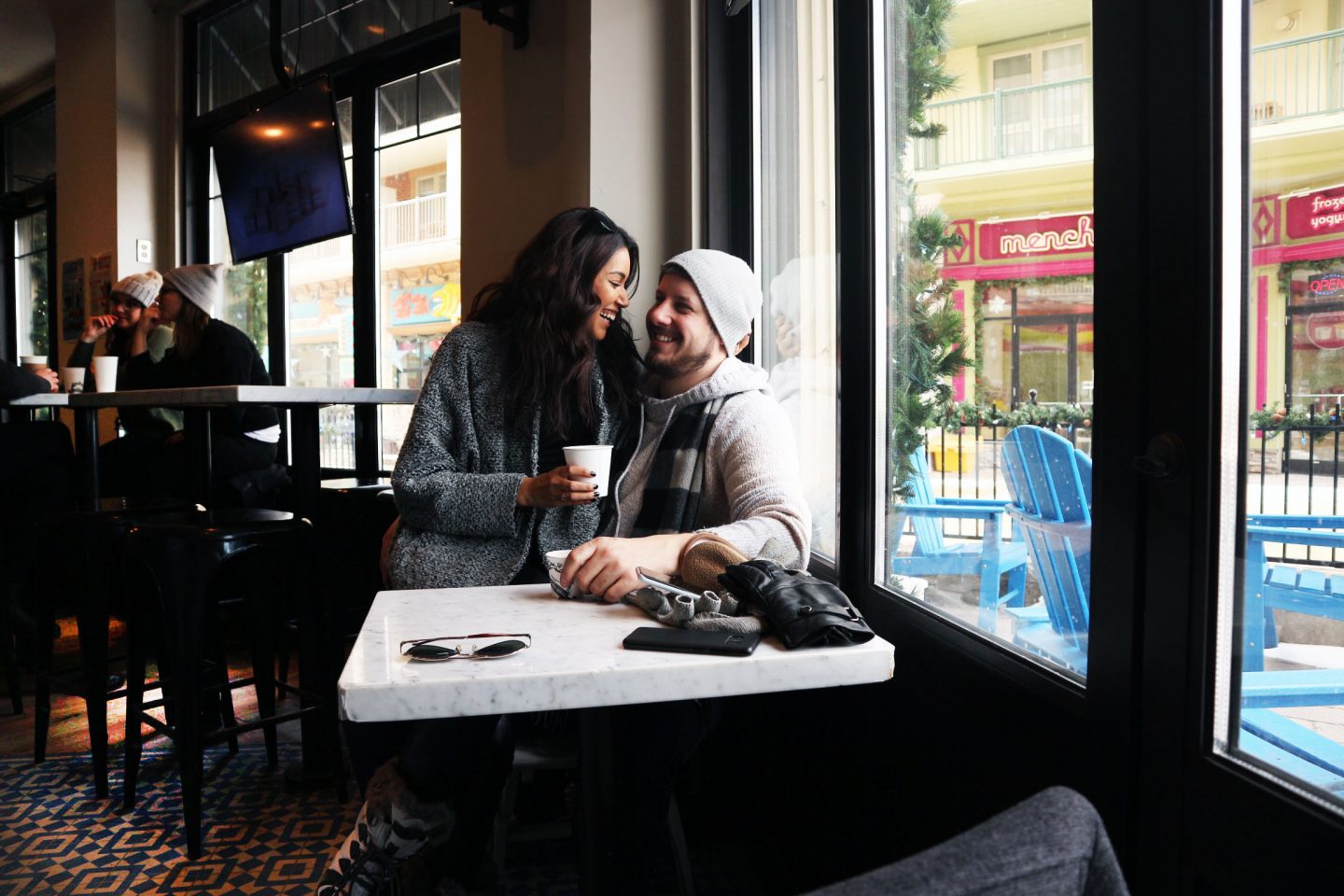 A couple seated together smiling at each other inside a cafe or restaurant.