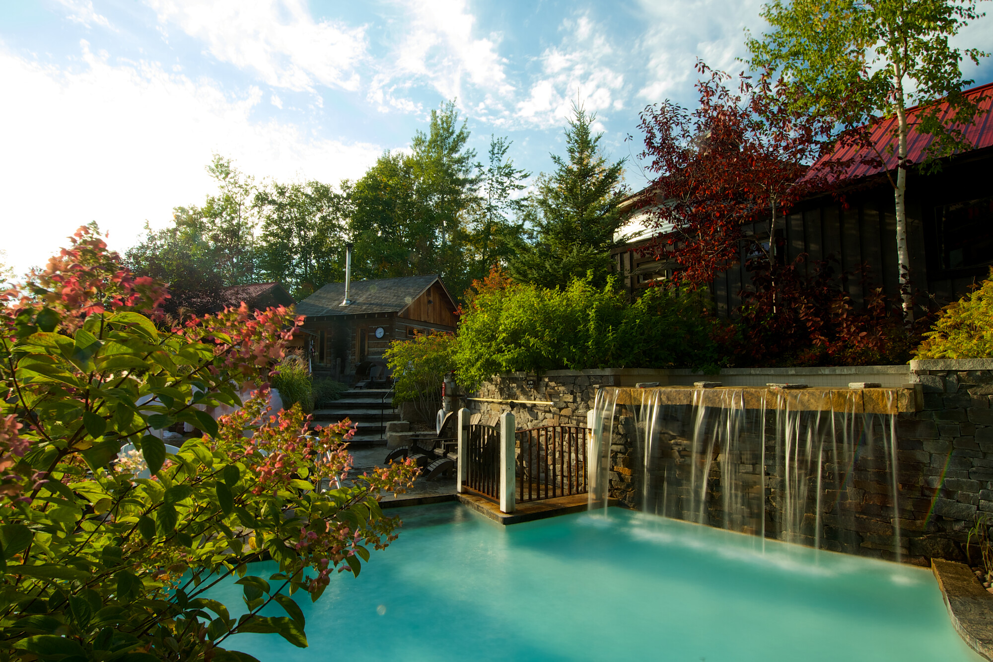 An outdoor spa on a bright day. Water gently cascades into an aquamarine pool.
