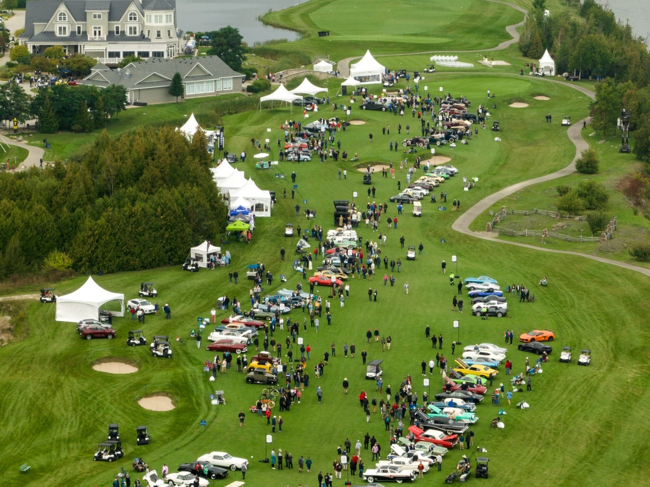 Aerial image of a car show held on a gold course. Spectators and cars line the fairway.