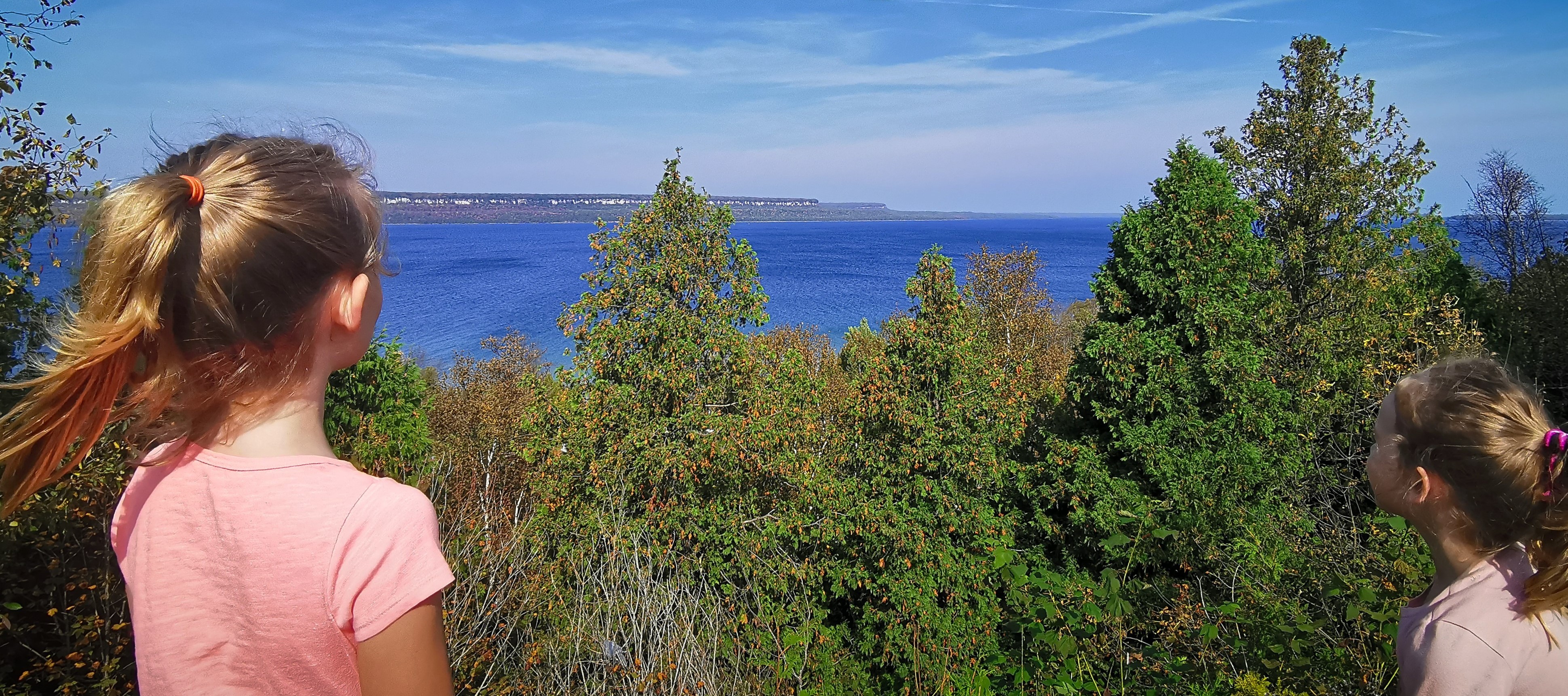 Two children look out over water from a lookout.