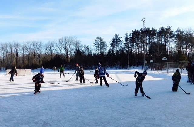 People playing hockey on an outdoor rink.