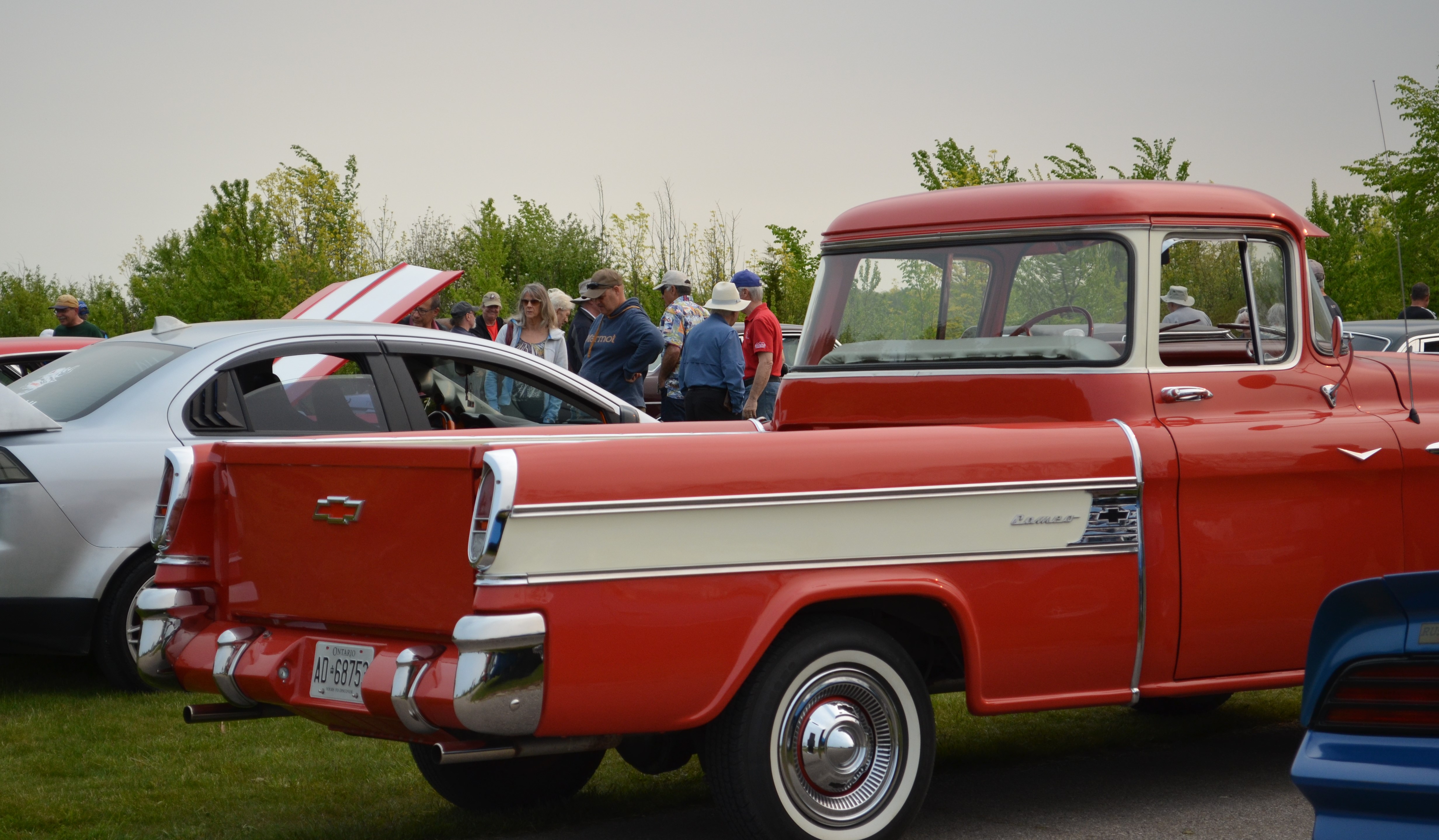 A red Chevrolet pickup truck at an outdoor car show.