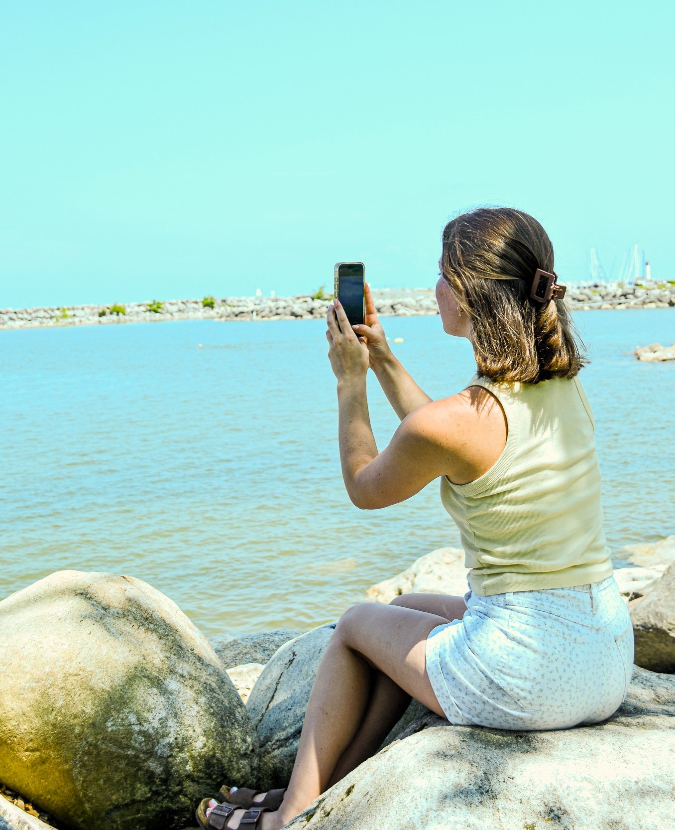 a girl taking a photo of the waterfront