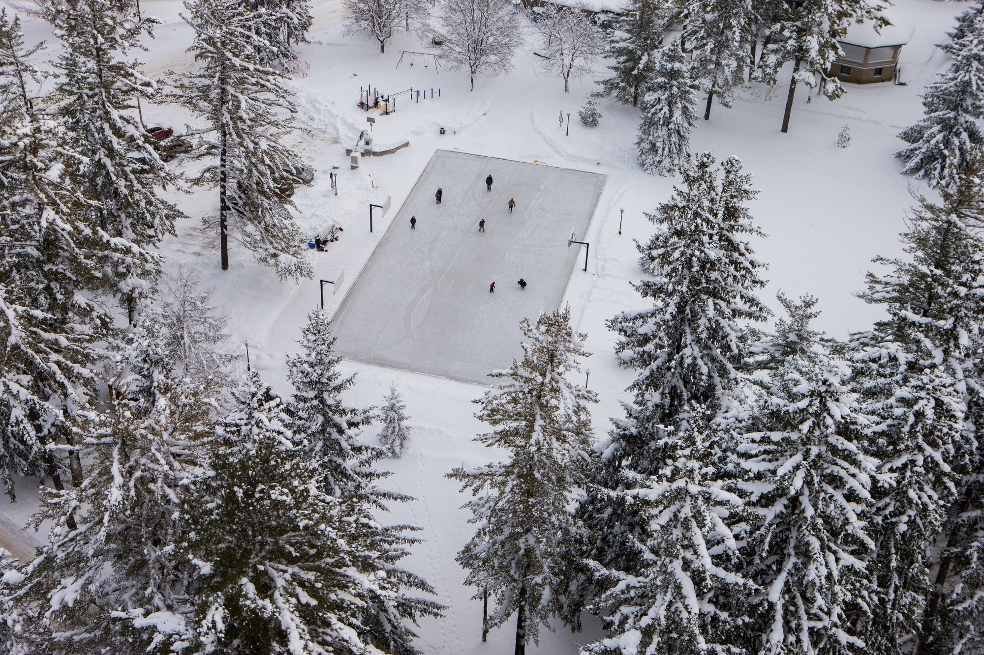 Aerial view of several people skating on an outdoor ice rink.
