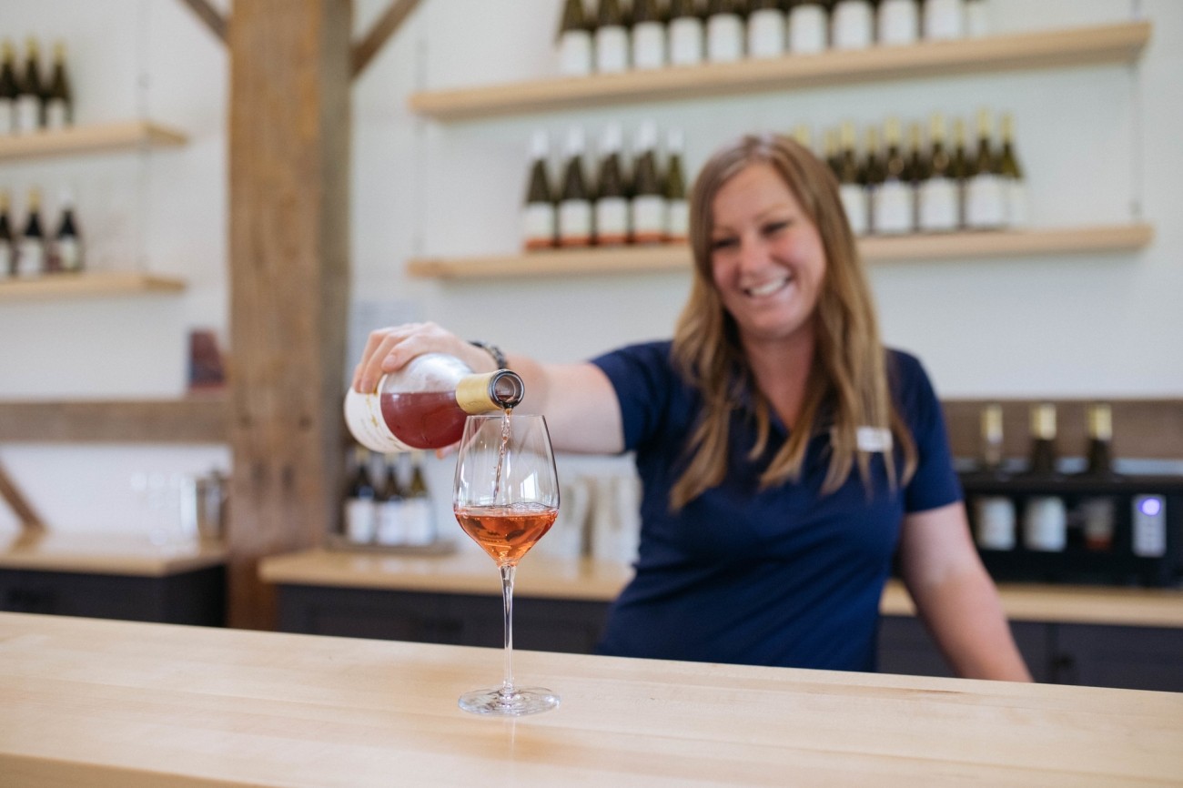 A server smiles while pouring a glass of wine.