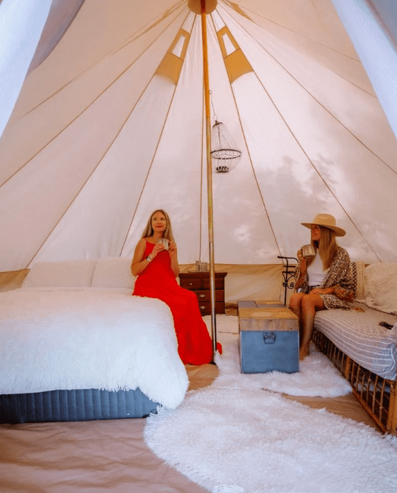 Interior of a yurt. Two people drink from mugs.