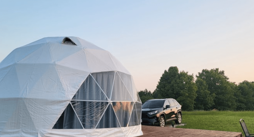 A vehicle parked beside a dome tent.