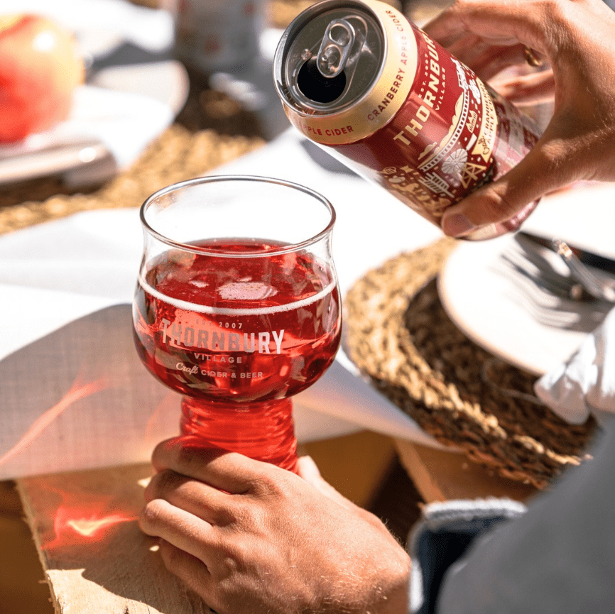 someone pouring a cider into a glass