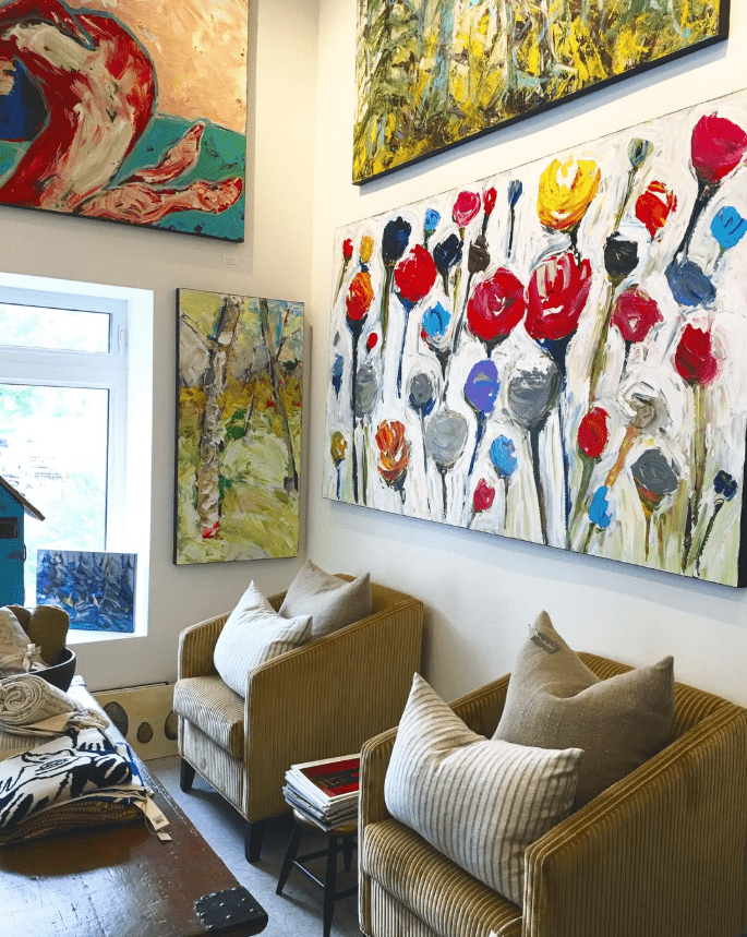 Interior of a gallery, paintings hung on walls around a sitting area.