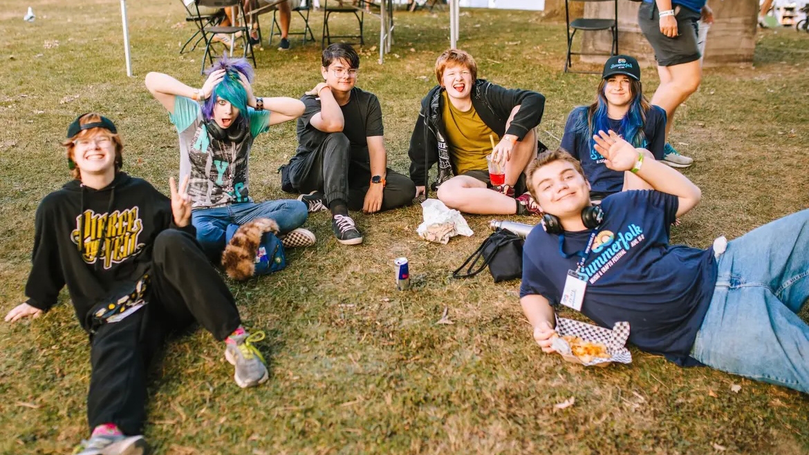 A group of volunteers relax on the ground at Summerfolk.