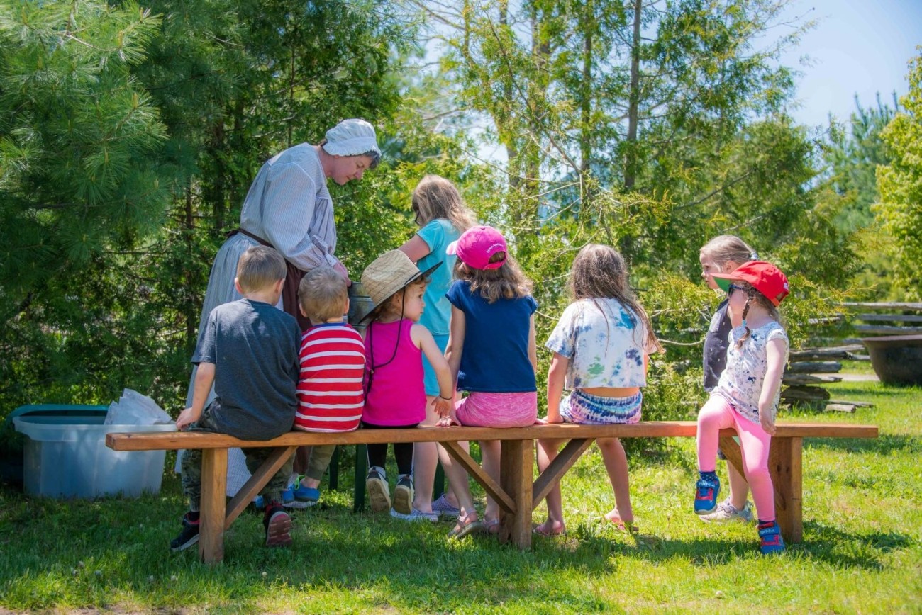 kids doing an activity with a historical interpreter during Spring Into Moreston event