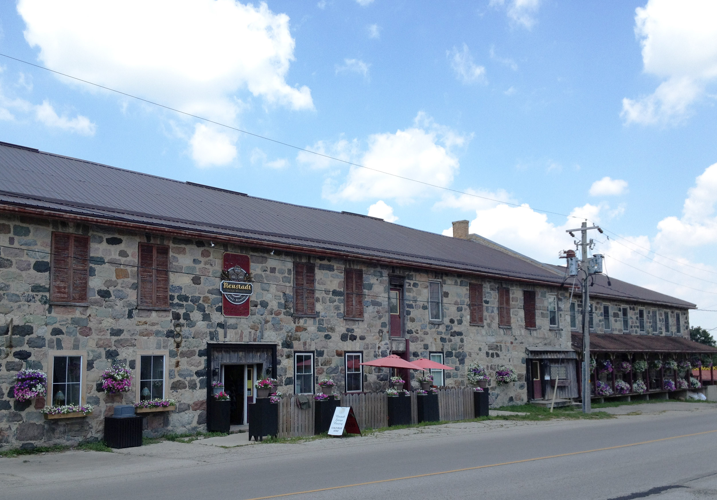 Long stone building with shuttered windows and flower planters along the street.