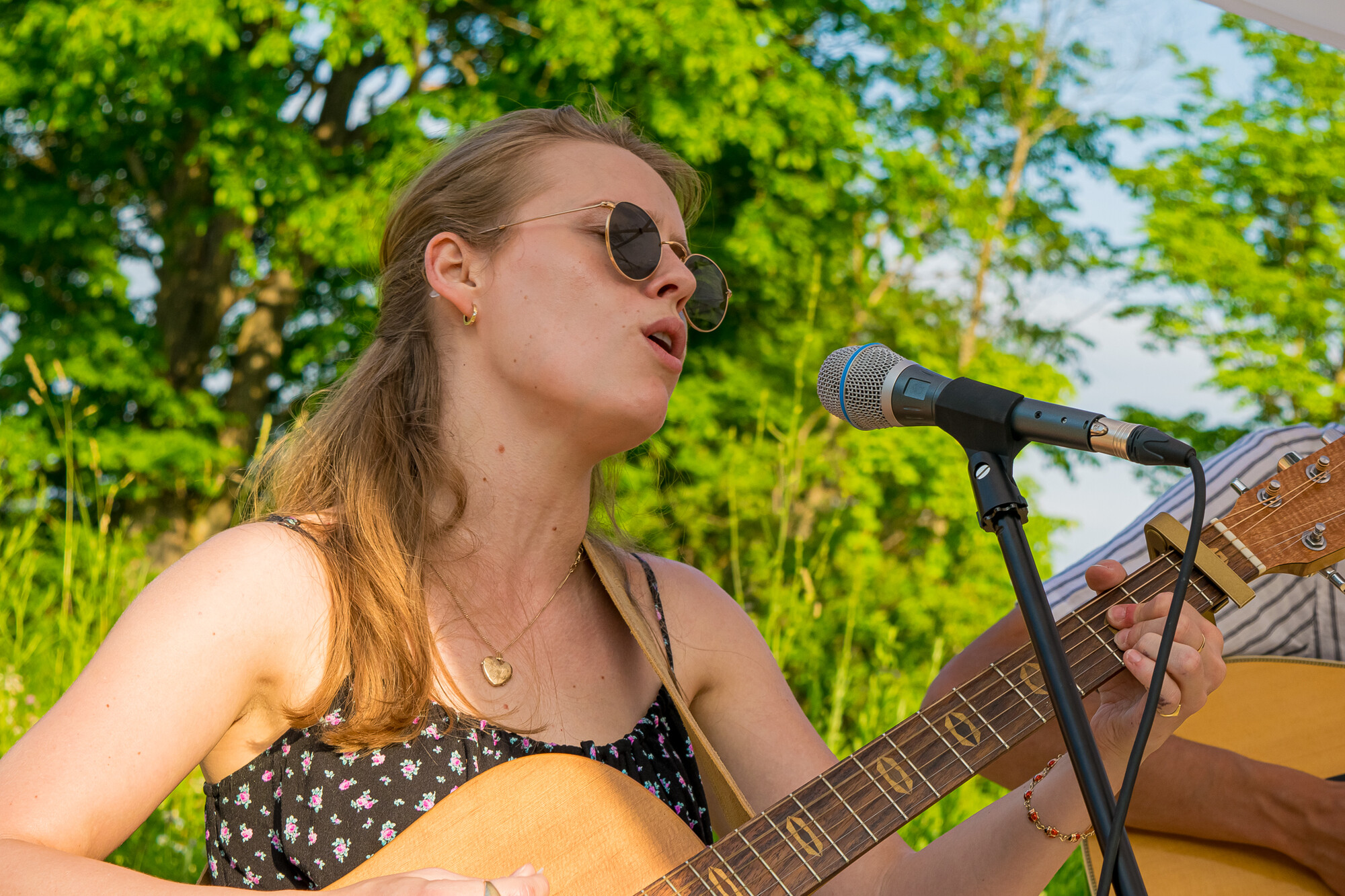 A performer sings and plays guitar outside.