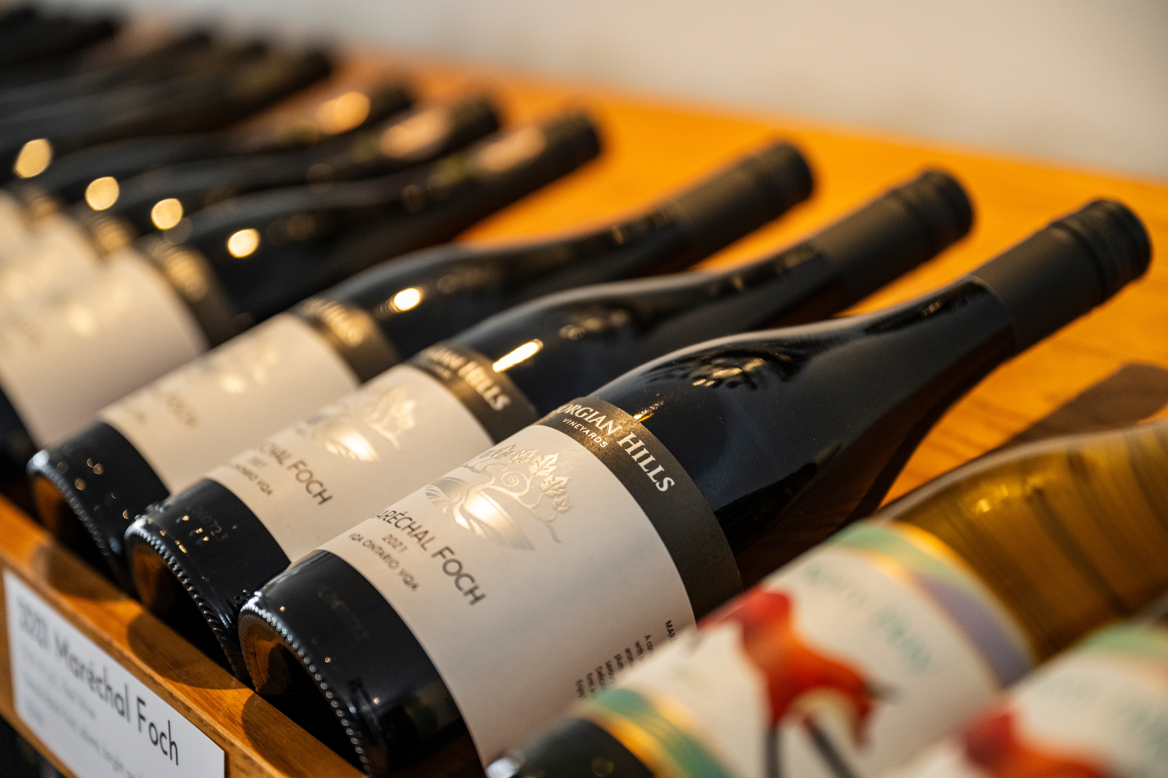 Close up image of wine bottles laying on a wooden wine rack