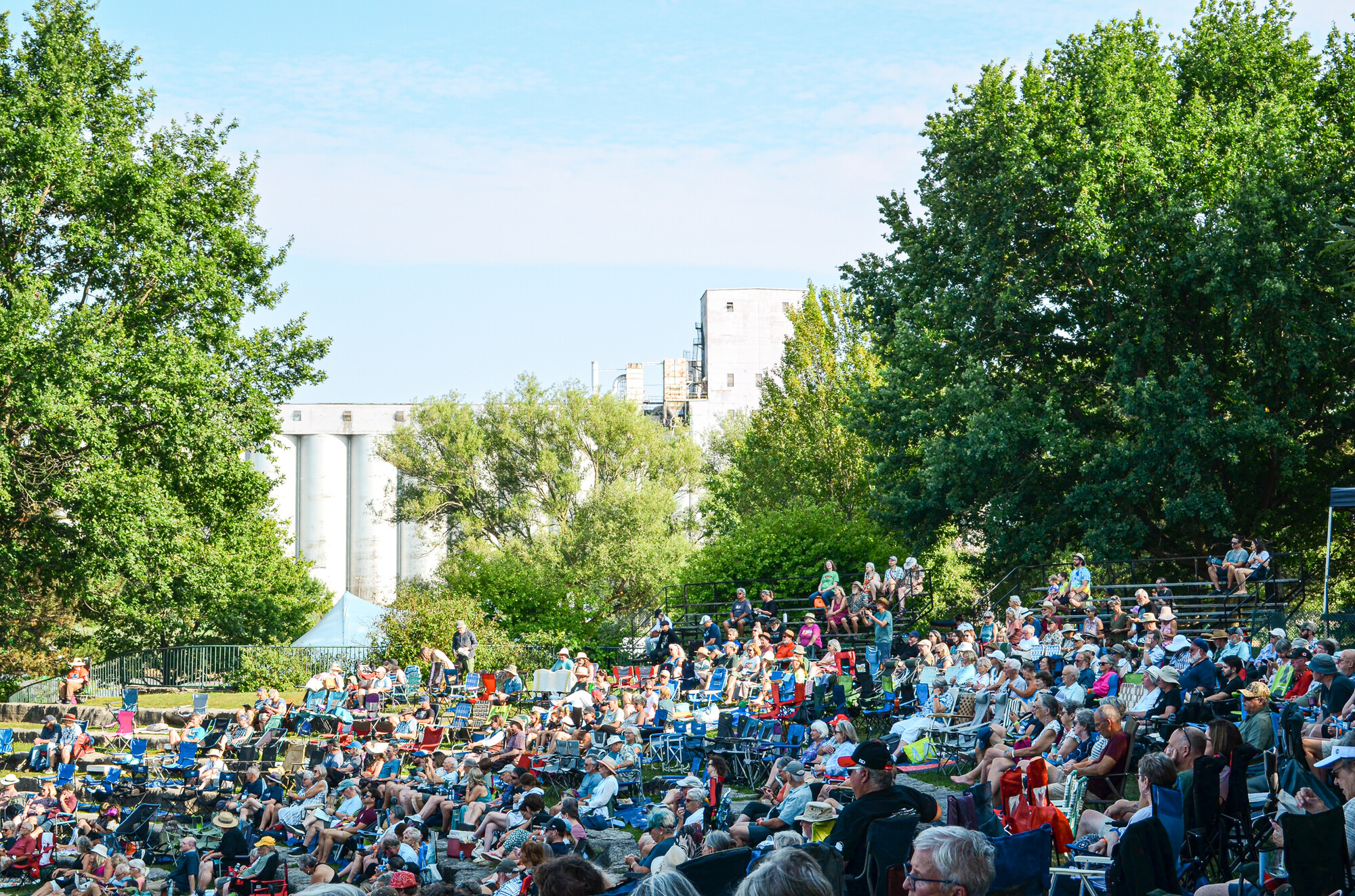 A large crowd seated at an outdoor festival on a bright summer day.