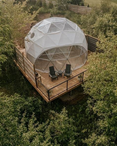 A dome shaped glamping room on a wooden platform in the woods.