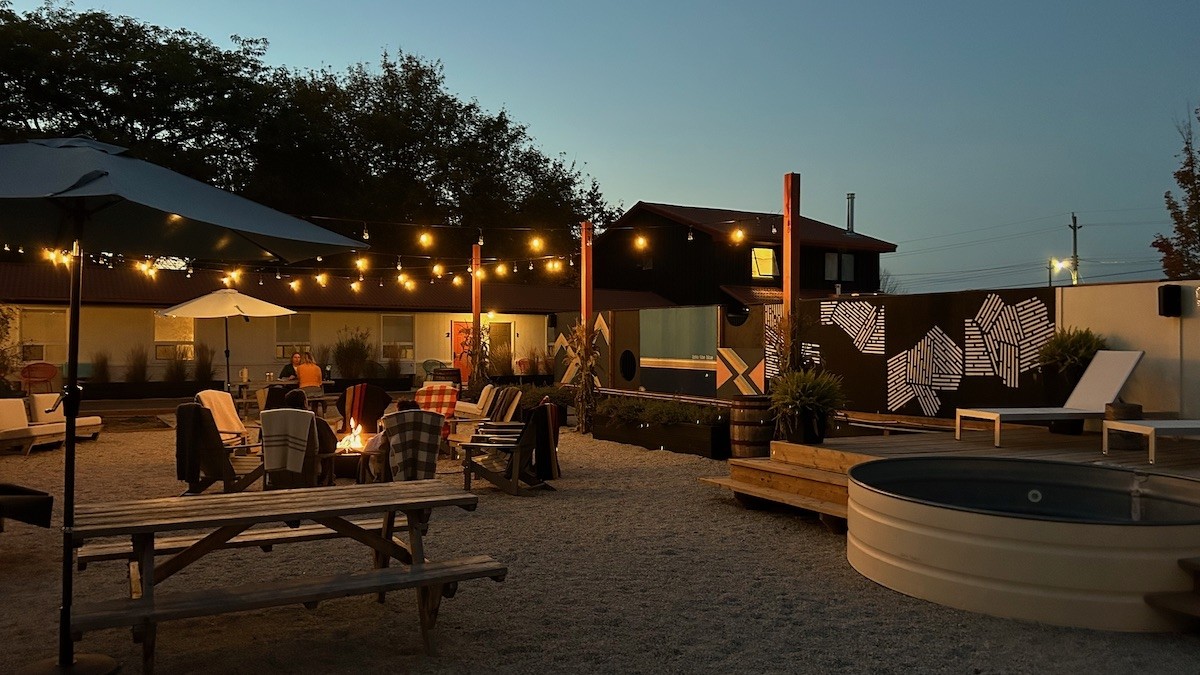 An outdoor recreation area with hot tub, firepit, picnic table and string lights.