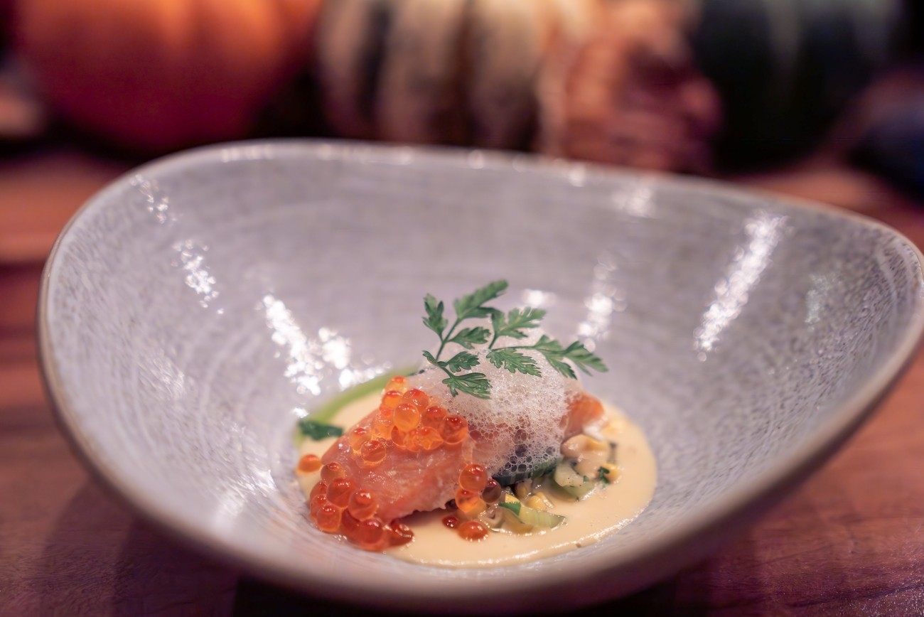 A garnished fish dish sits deep in a pottery bowl.