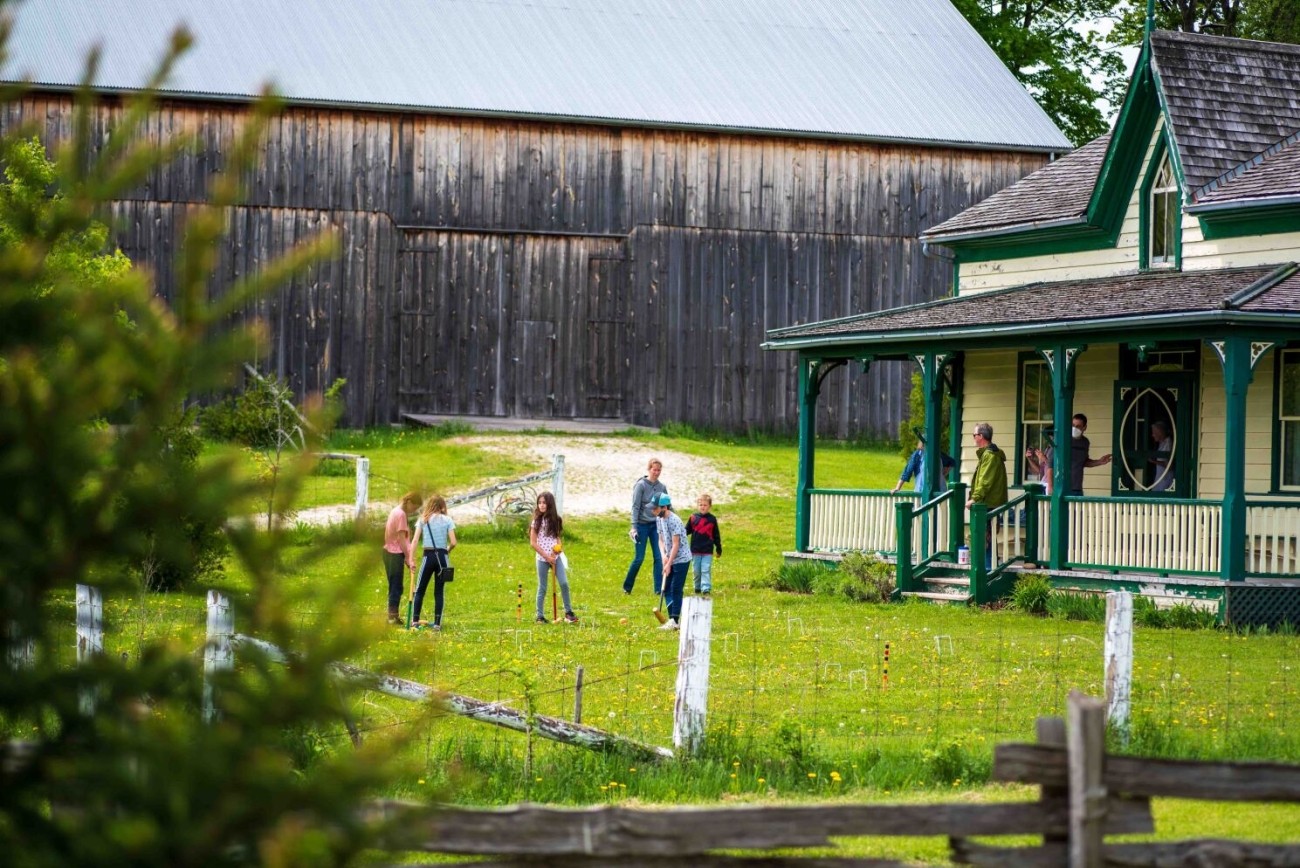 A group playing croquet on the lawn in front of a historic building.