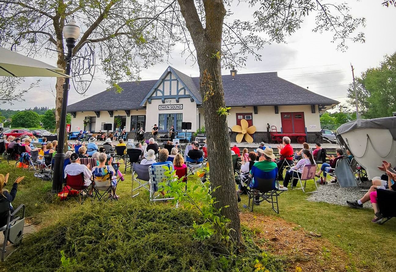 a crowd of people sitting listening to live music outside