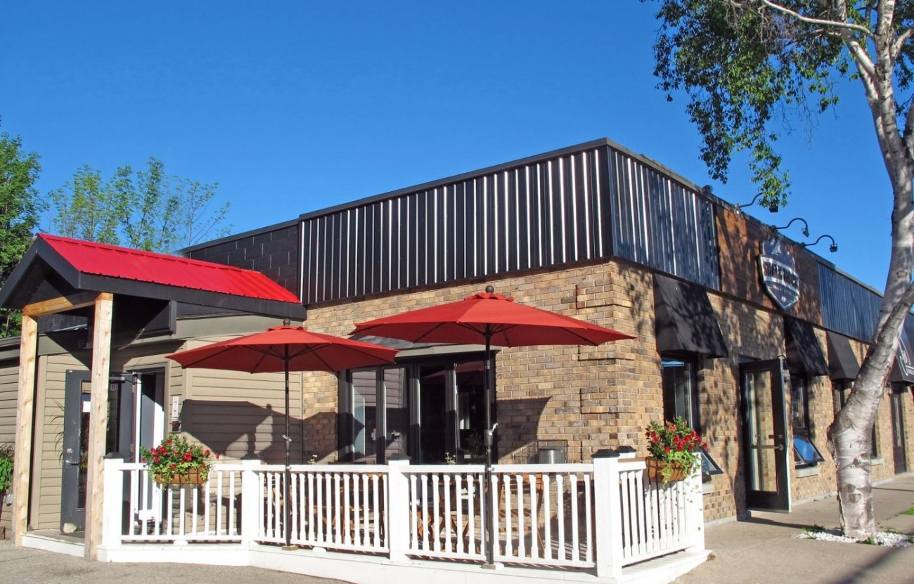 Exterior shot of a building with patio and red umbrellas.